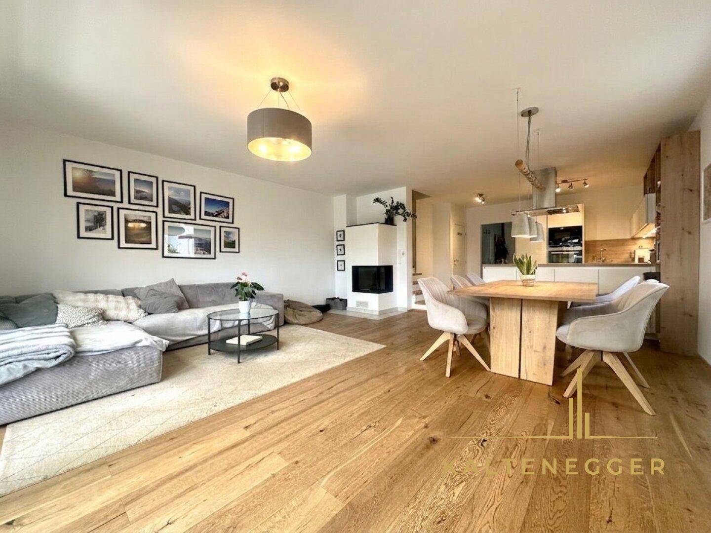 Offener Wohn- und Essbereich mit Holzboden, Kamin und moderner Einrichtung, ideal für gesellige Abende.