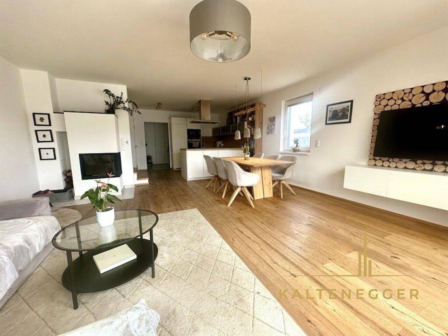 Geräumiger Wohn-Essbereich mit Kamin, Holzboden und Zugang zur Terrasse, perfekt für Familienleben.