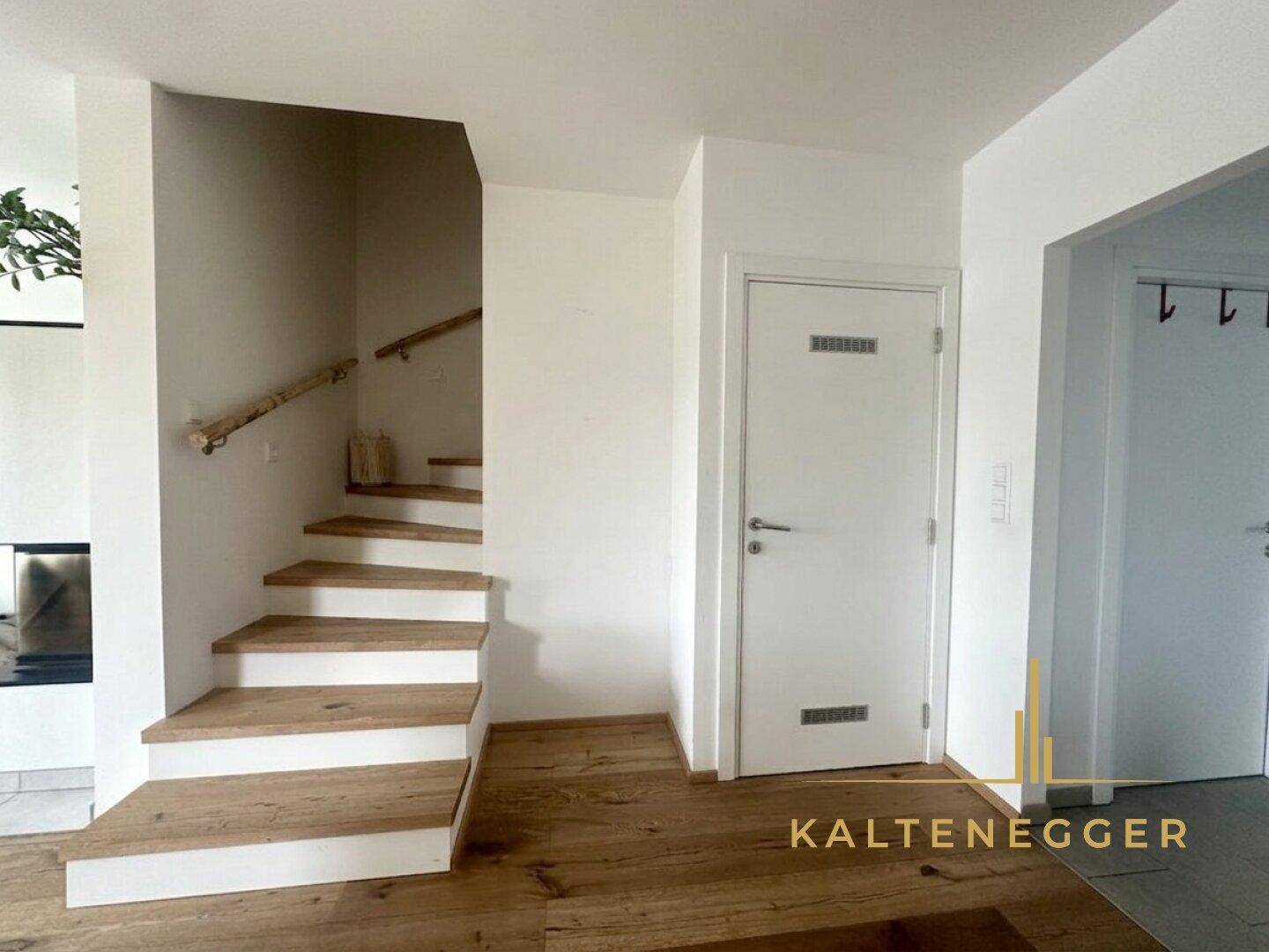 Heller Flur mit Holztreppe und modernem Holzboden, der die verschiedenen Ebenen des Hauses verbindet.