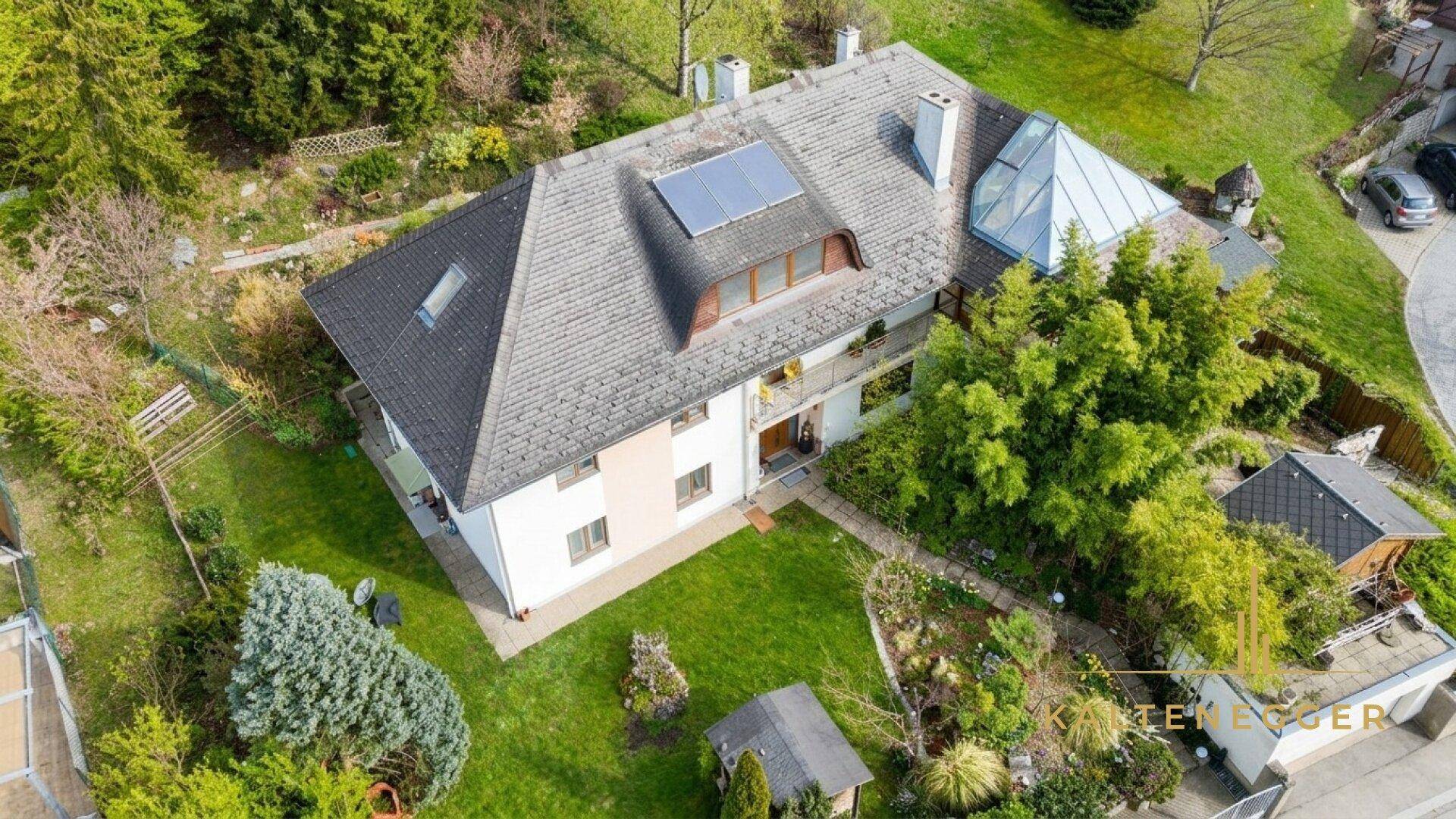 Luftaufnahme eines Hauses mit großem Garten, umgeben von viel Grün und Bäumen.