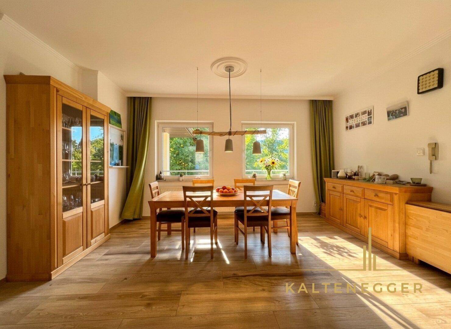 Heller Essbereich mit Holztisch, passenden Möbeln und Blick ins Grüne durch die Fenster.