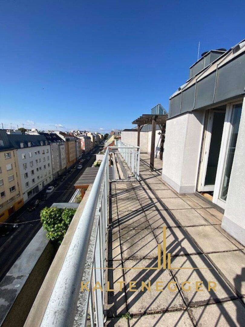 Langer Balkon mit Fliesenboden entlang des Gebäudes, bietet eine weite Aussicht auf die Stadt und die Straße.