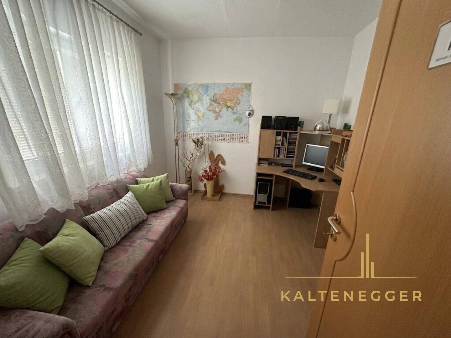 Arbeitszimmer mit Sofa, Schreibtisch, Computer und einer Weltkarte an der Wand für Inspiration.