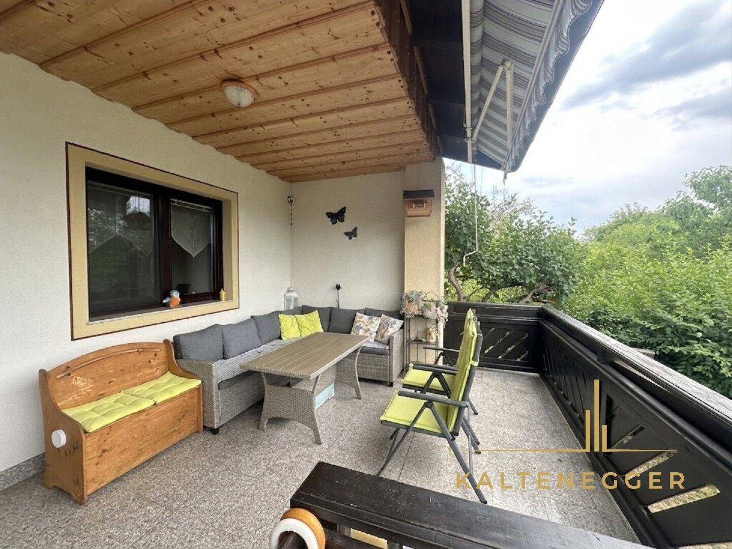 Gemütlicher Balkon mit Holzdecke und bequemen Outdoor-Sitzmöbeln für entspannte Stunden im Freien.
