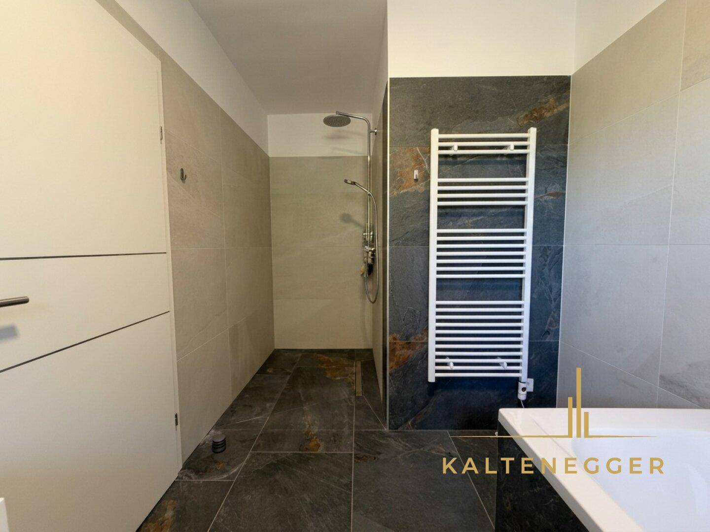 Elegantes Badezimmer mit ebenerdiger Dusche und modernem beheiztem Handtuchhalter.