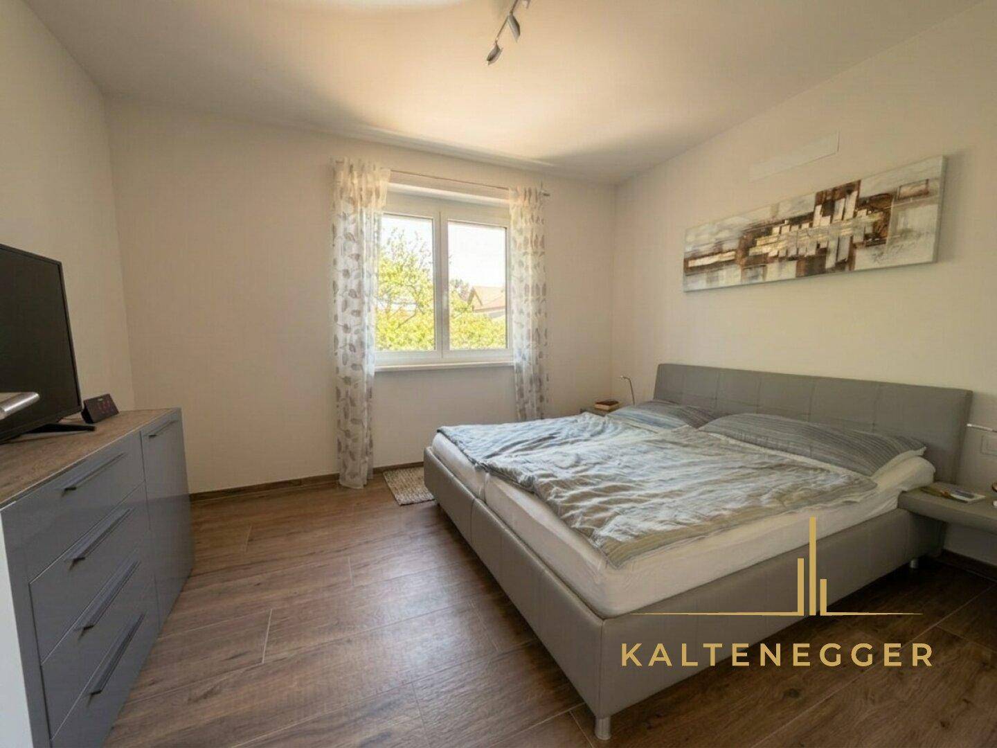 Gemütliches Schlafzimmer mit Doppelbett, Kommode und Fenster, das viel Licht spendet.