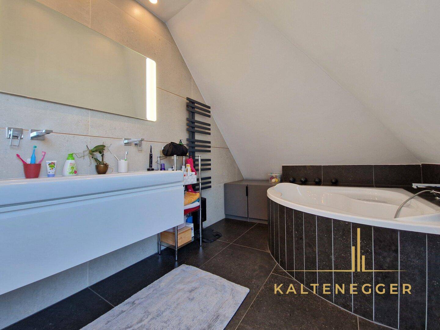 Modernes Badezimmer mit Badewanne, Waschtisch und beheiztem Handtuchhalter im Dachgeschoss.