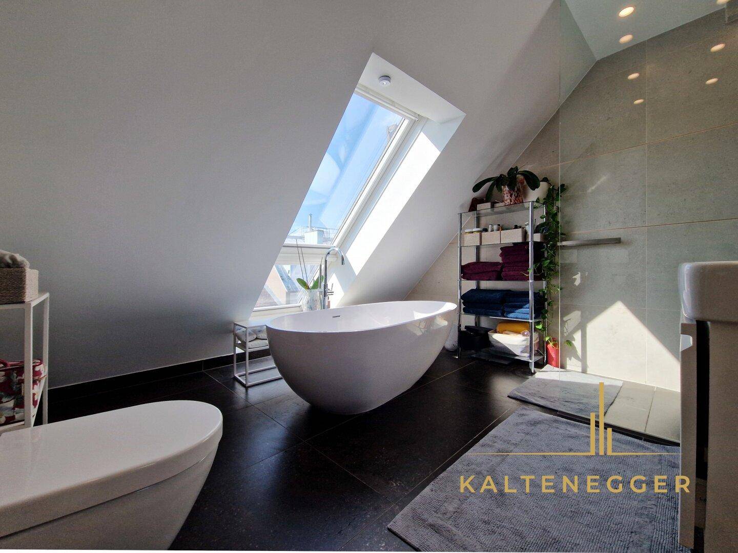 Helles Badezimmer im Dachgeschoss mit freistehender Badewanne und Dachfenster.