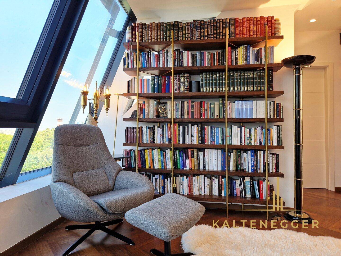 Gemütliche Leseecke mit Sessel und umfangreichem Bücherregal unter schrägen Fenstern.