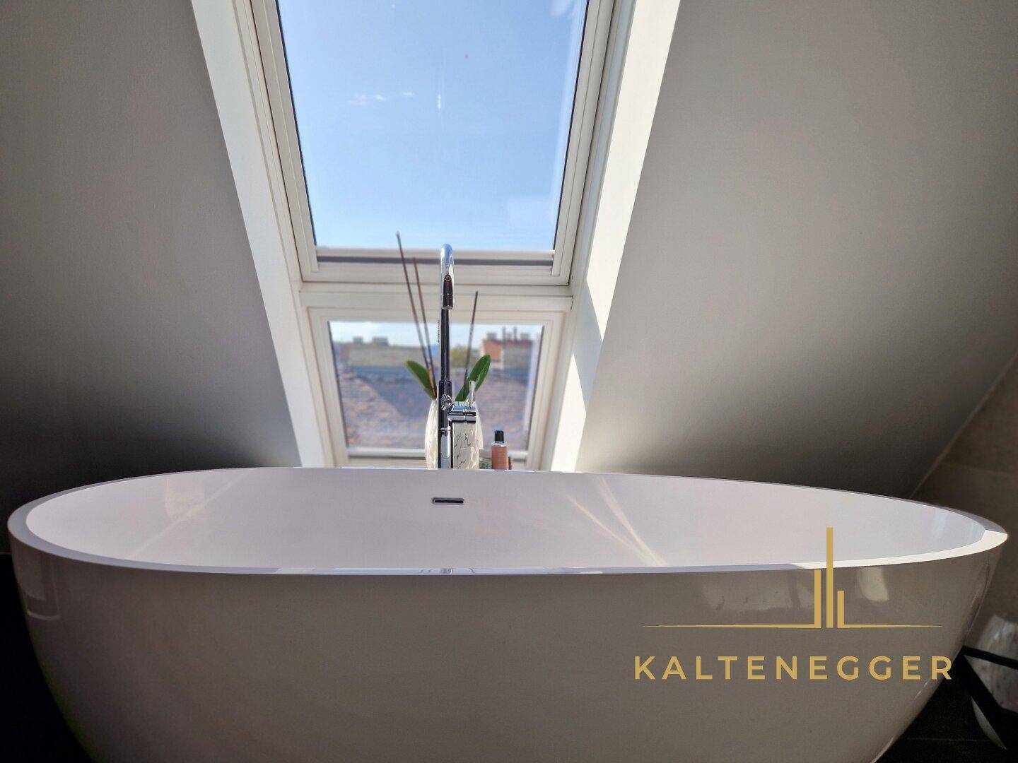 Elegante freistehende Badewanne unter einem großen Dachfenster für entspannende Momente.