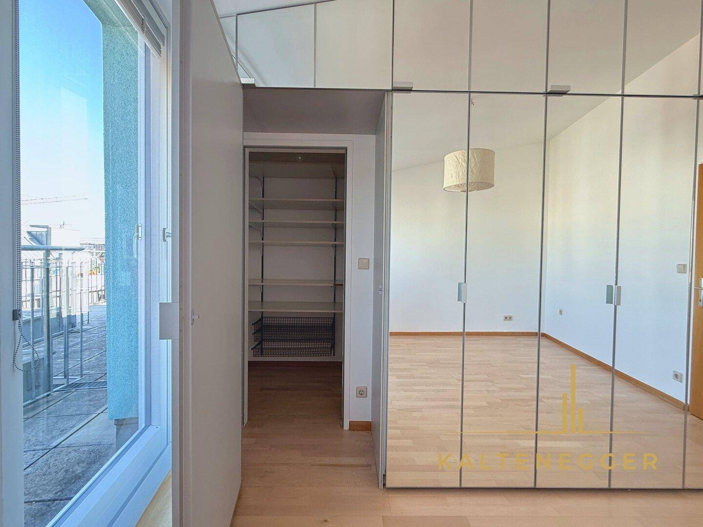 Schlafzimmer mit Spiegelschränken und Blick auf den begehbaren Kleiderschrank.