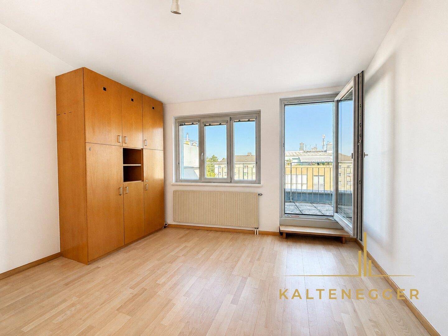 Schlafzimmer mit Holzeinbauschränken, Parkettboden und Zugang zu einem französischen Balkon.