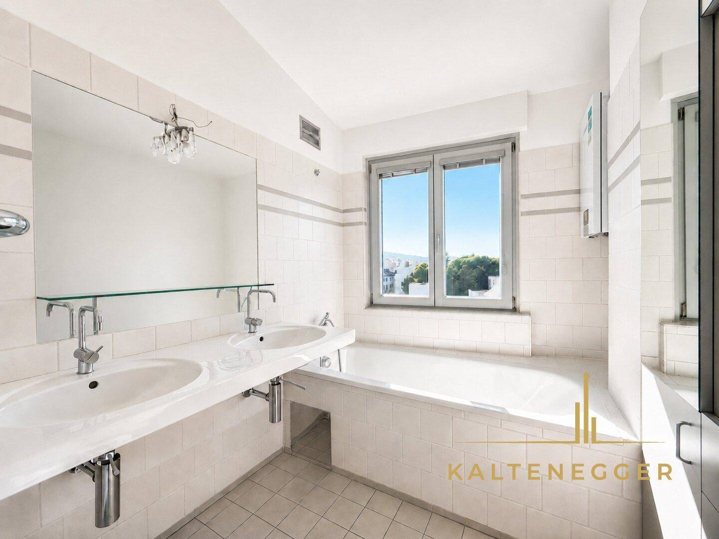 Geräumiges Badezimmer mit Doppelwaschbecken, Badewanne und Fenster mit Ausblick.