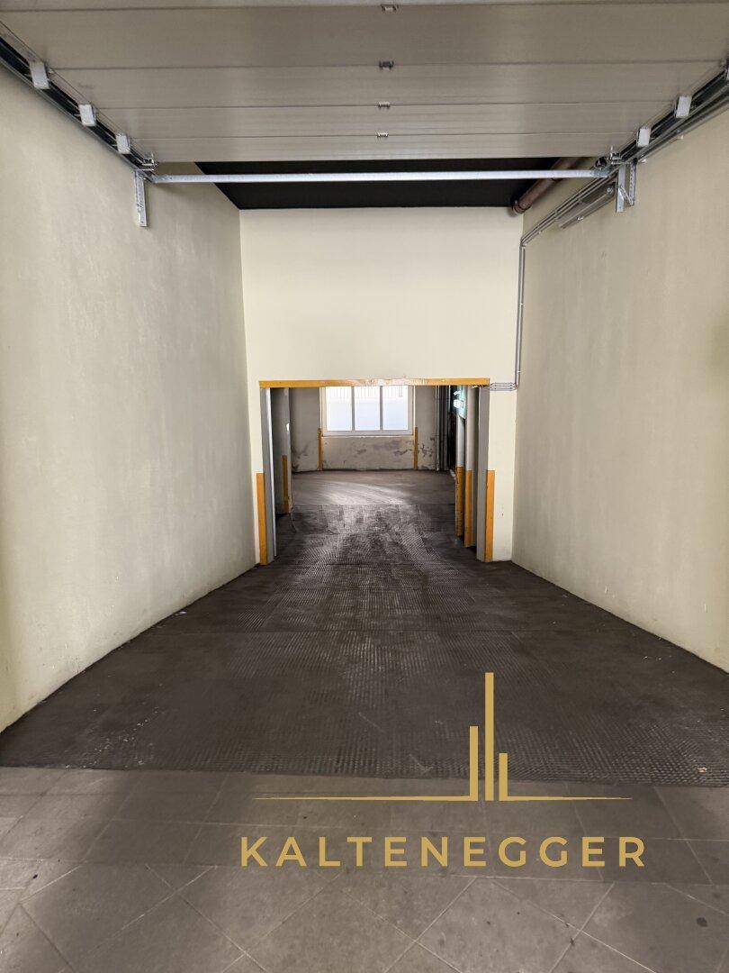 Langer, leerer Garagenzugang mit Rampe und hellen Wänden, der zu weiteren Räumen führt.