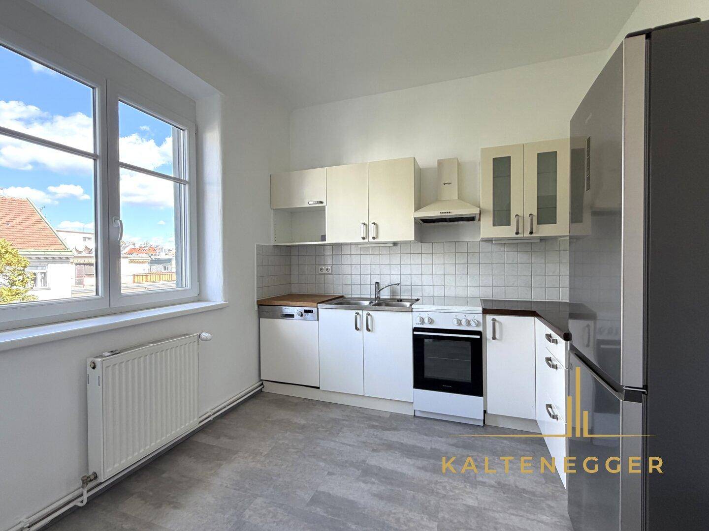 Funktionale Küche mit weißen Schränken, Fliesenrückwand und Blick aus dem Fenster.