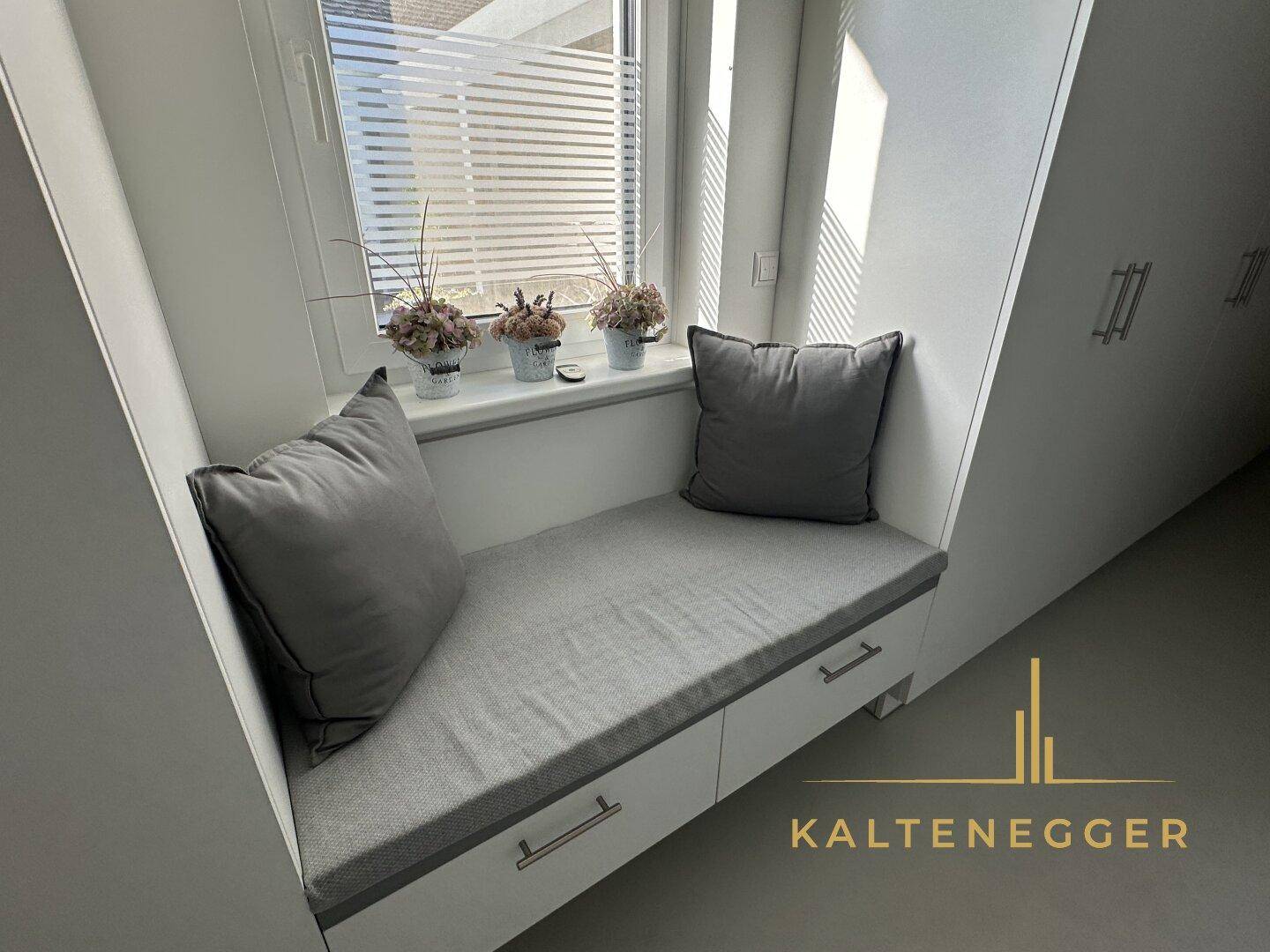Gemütlicher Fensterplatz mit Kissen und Stauraum, ideal zum Entspannen.