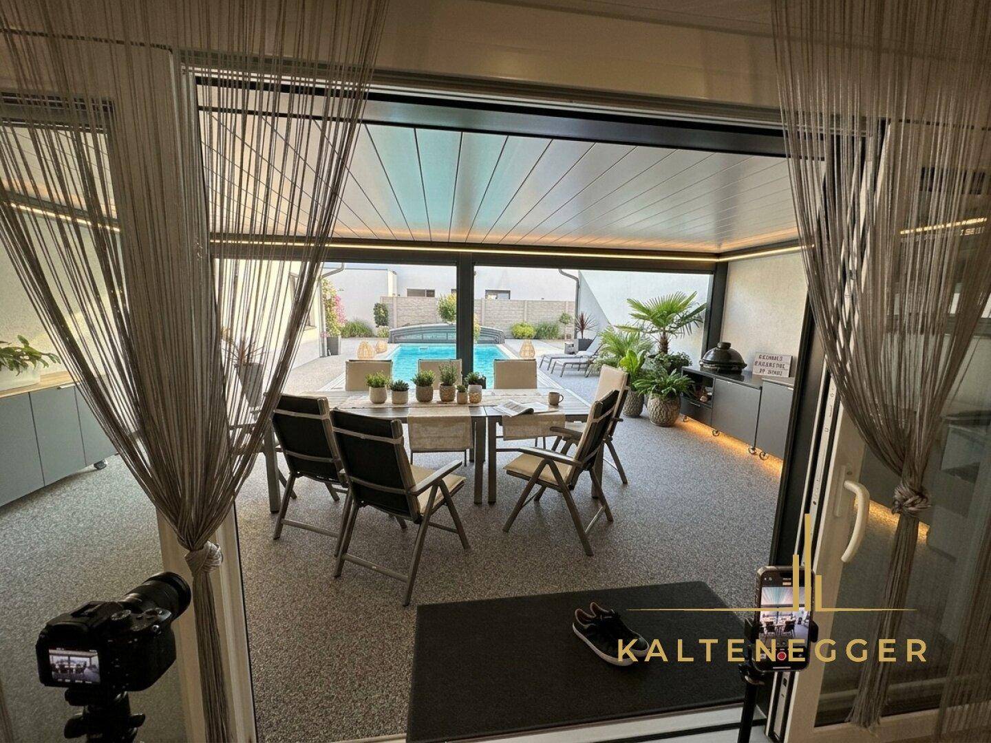 Überdachte Terrasse mit Esstisch und Blick auf den Pool, ideal für Mahlzeiten im Freien.