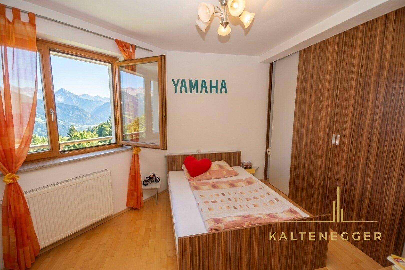 Gemütliches Schlafzimmer mit Holzboden, modernem Bett und beeindruckendem Bergblick durch das Fenster.