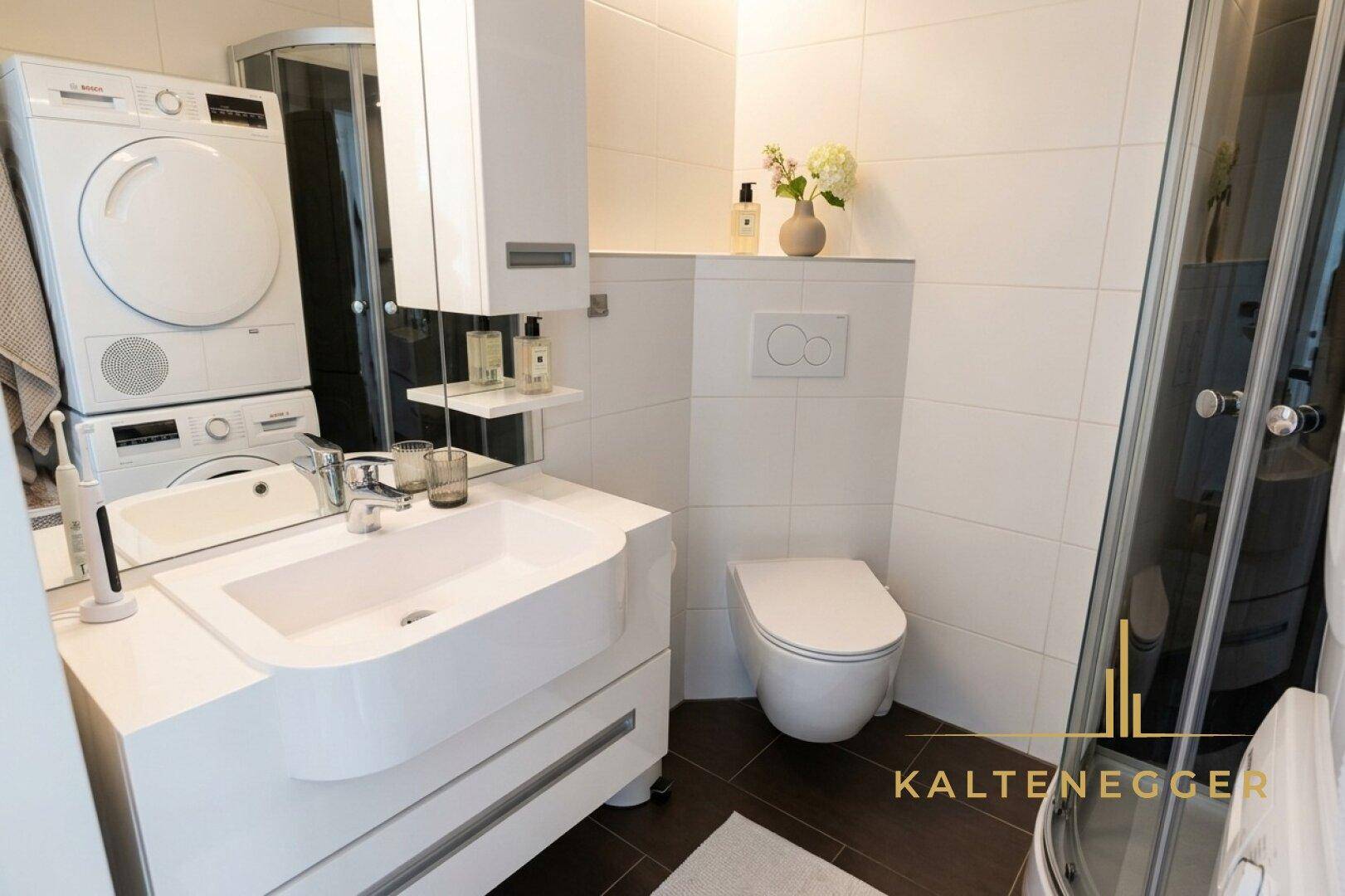 Modernes Badezimmer mit Dusche, Waschbecken, wandhängender Toilette und integrierter Waschmaschine.