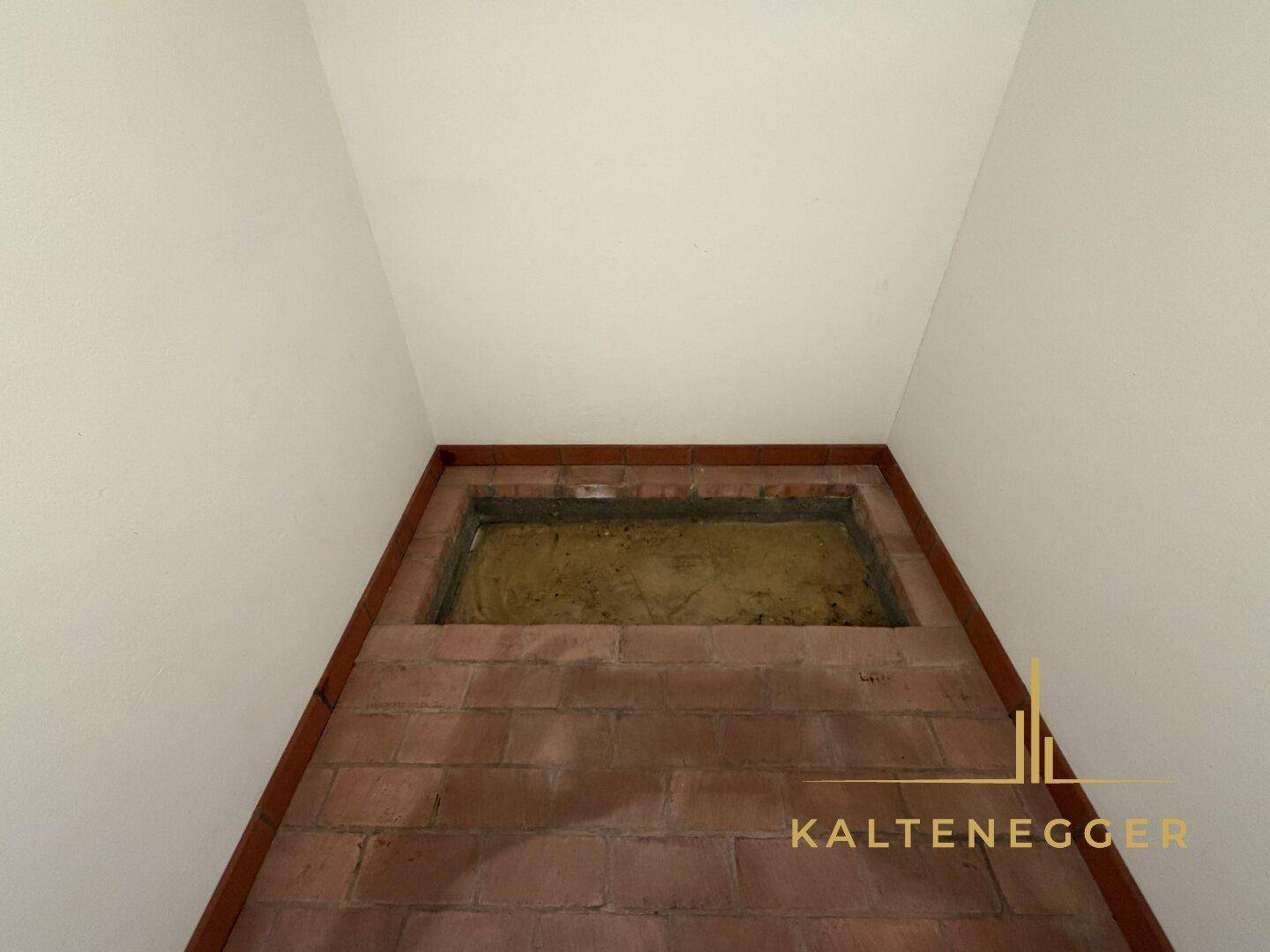 Kleiner, gemauerter Kellerraum oder Lagerbereich mit Ziegelwänden und einfachem Boden.