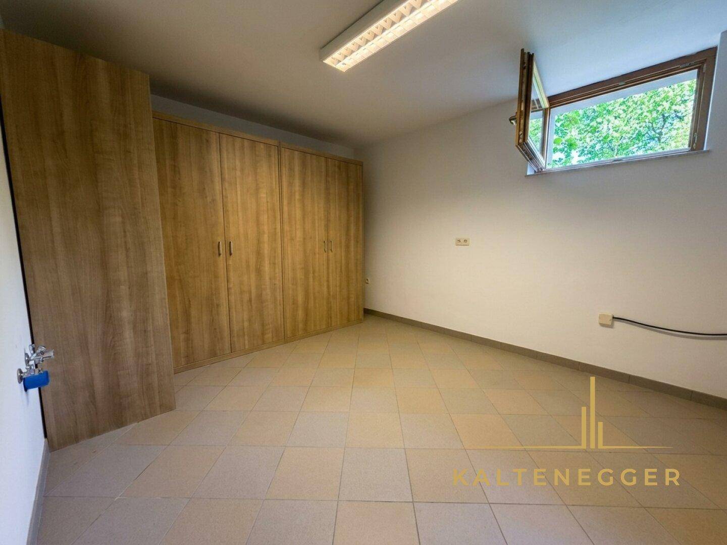 Kellerraum mit Fliesenboden, praktischen Einbauschränken und einem kleinen Fenster für Belüftung.