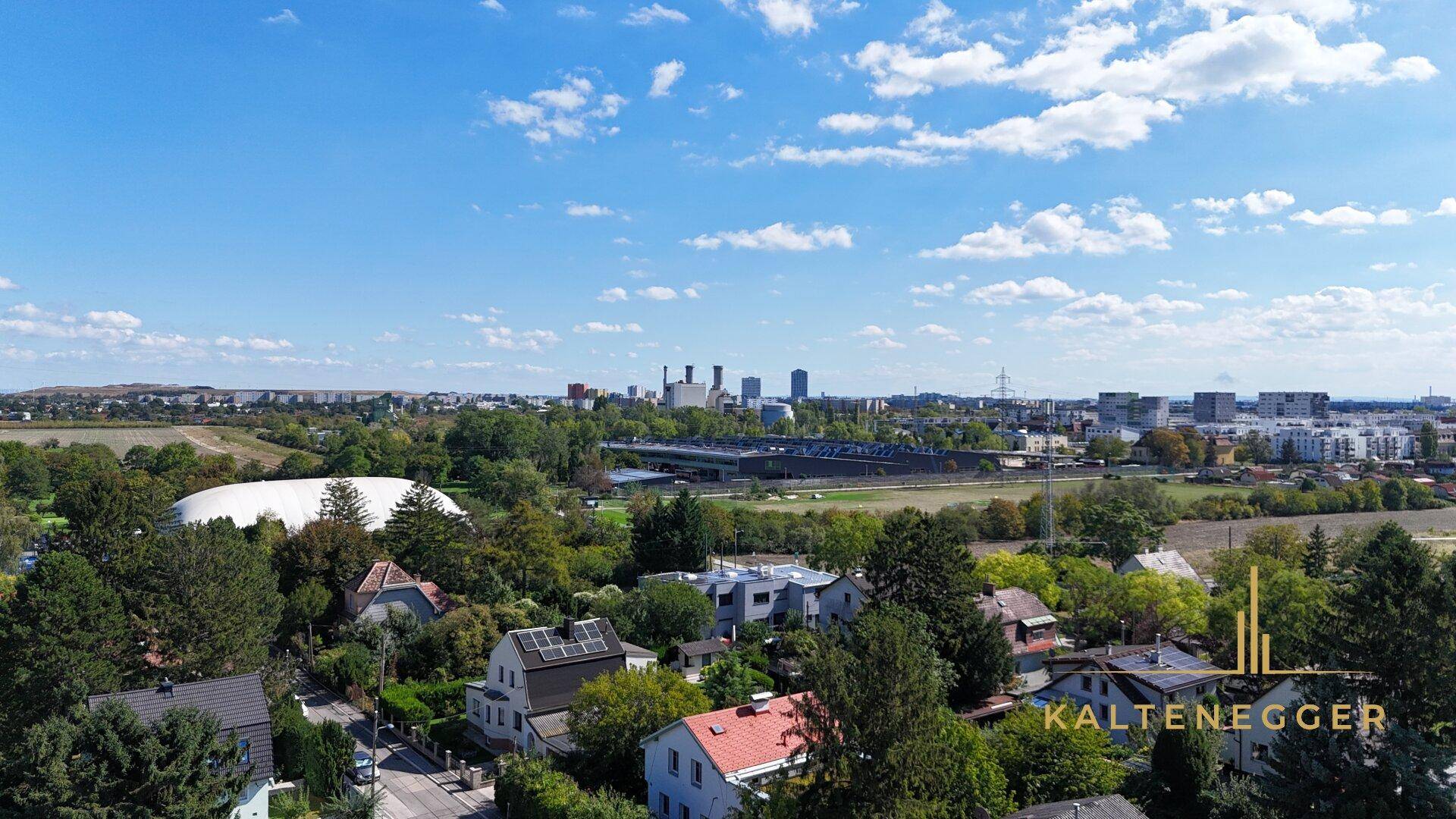 Panoramablick über eine Wohngegend mit städtischer Skyline und Industriegebäuden in der Ferne.