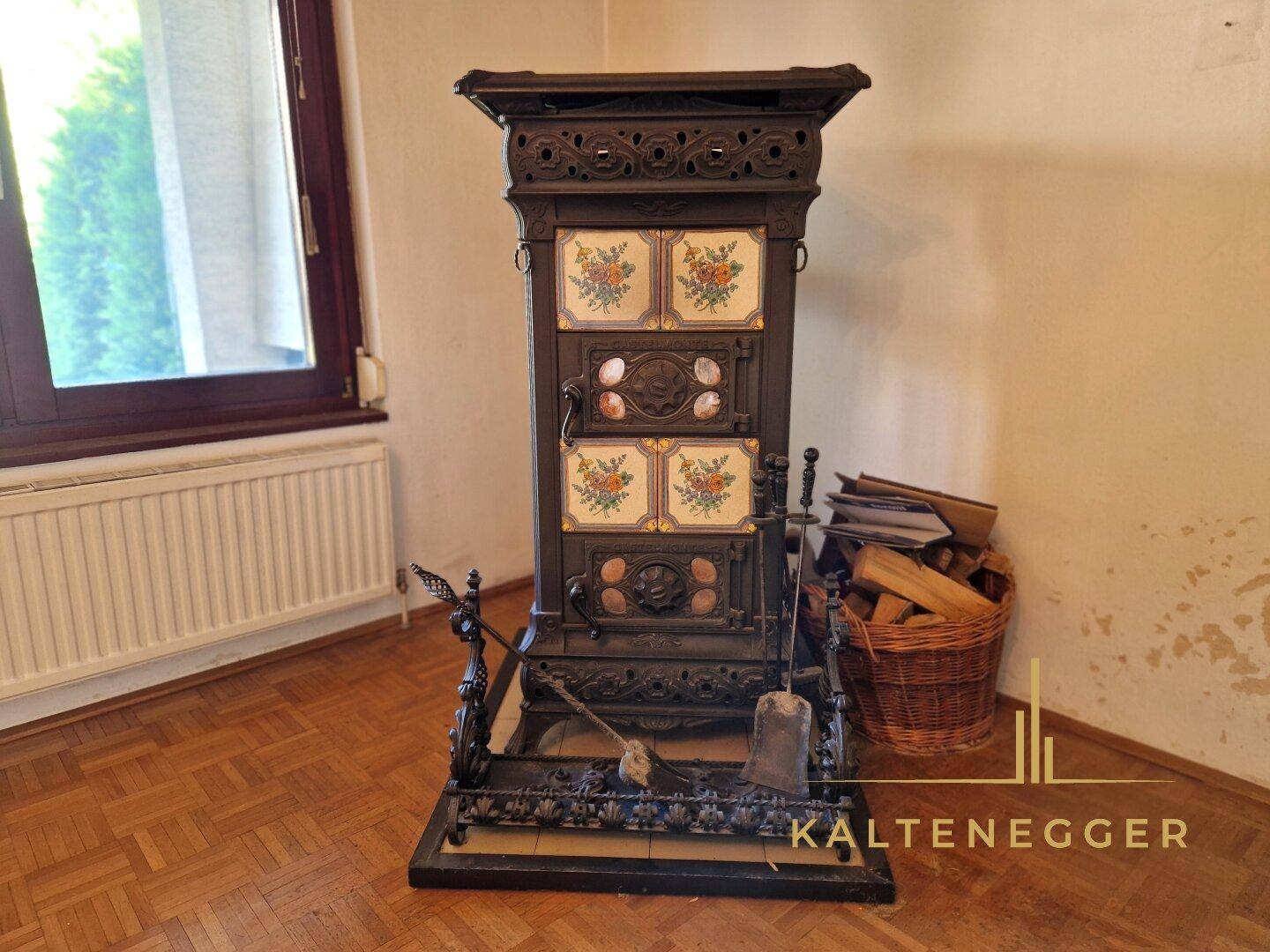 Traditioneller Kaminofen mit floralen Kacheln im Wohnzimmer, umgeben von Holzscheiten.