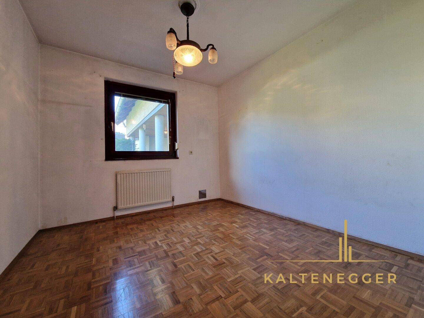 Schlafzimmer mit Parkettboden, Fenster und Heizkörper, bereit zur individuellen Gestaltung.