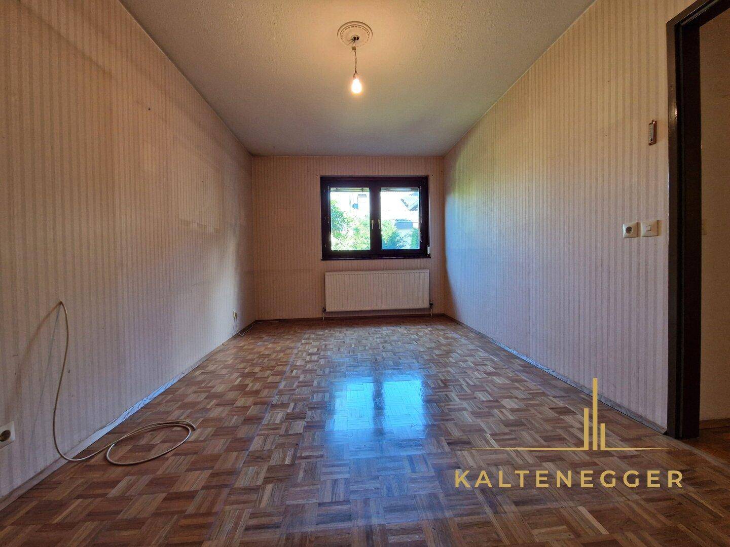 Geräumiges Schlafzimmer mit Parkettboden und Fenster, das viel Tageslicht hereinlässt.