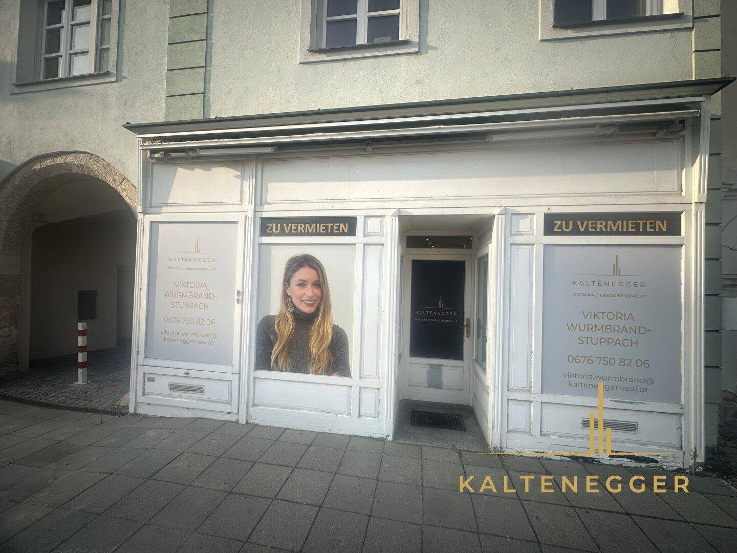 Nahaufnahme der Geschäftsfassade mit großen Schaufenstern und Vermietungsanzeigen.