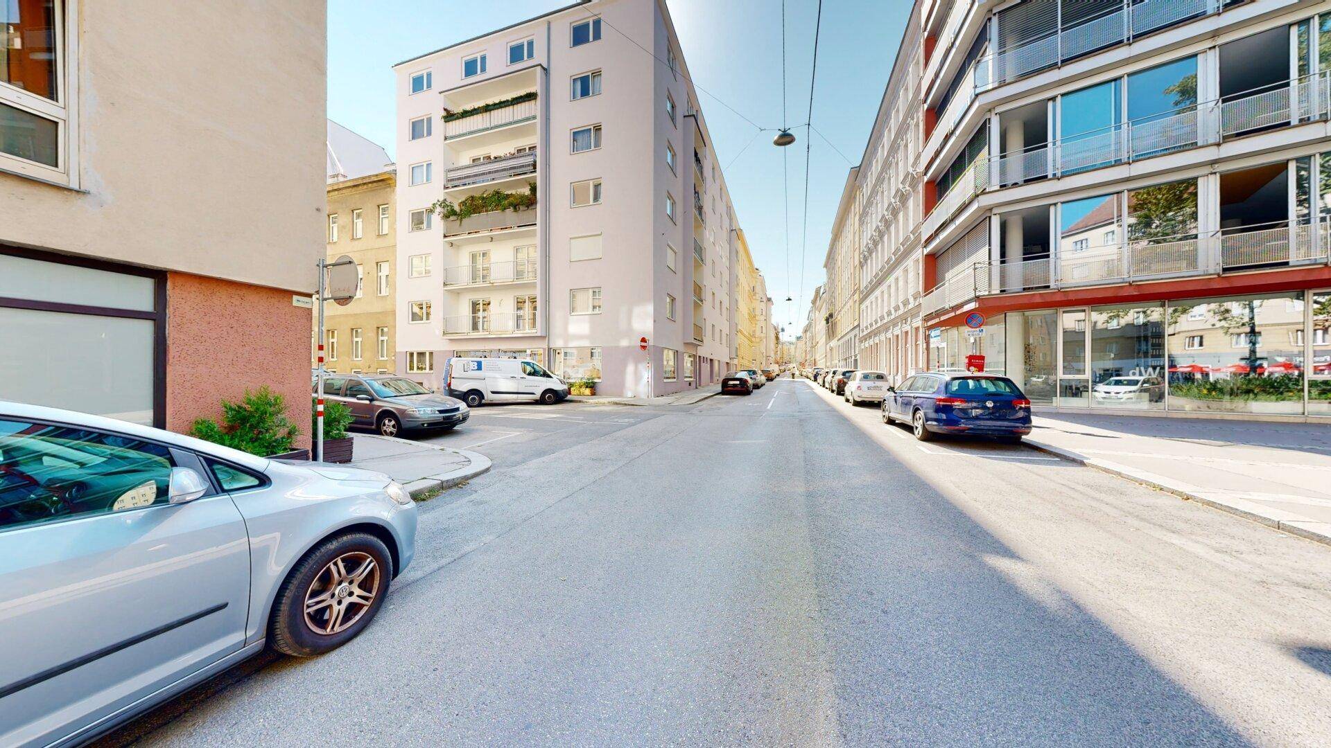 Ruhige Wohnstraße mit geparkten Autos und Mehrfamilienhäusern in städtischer Umgebung.