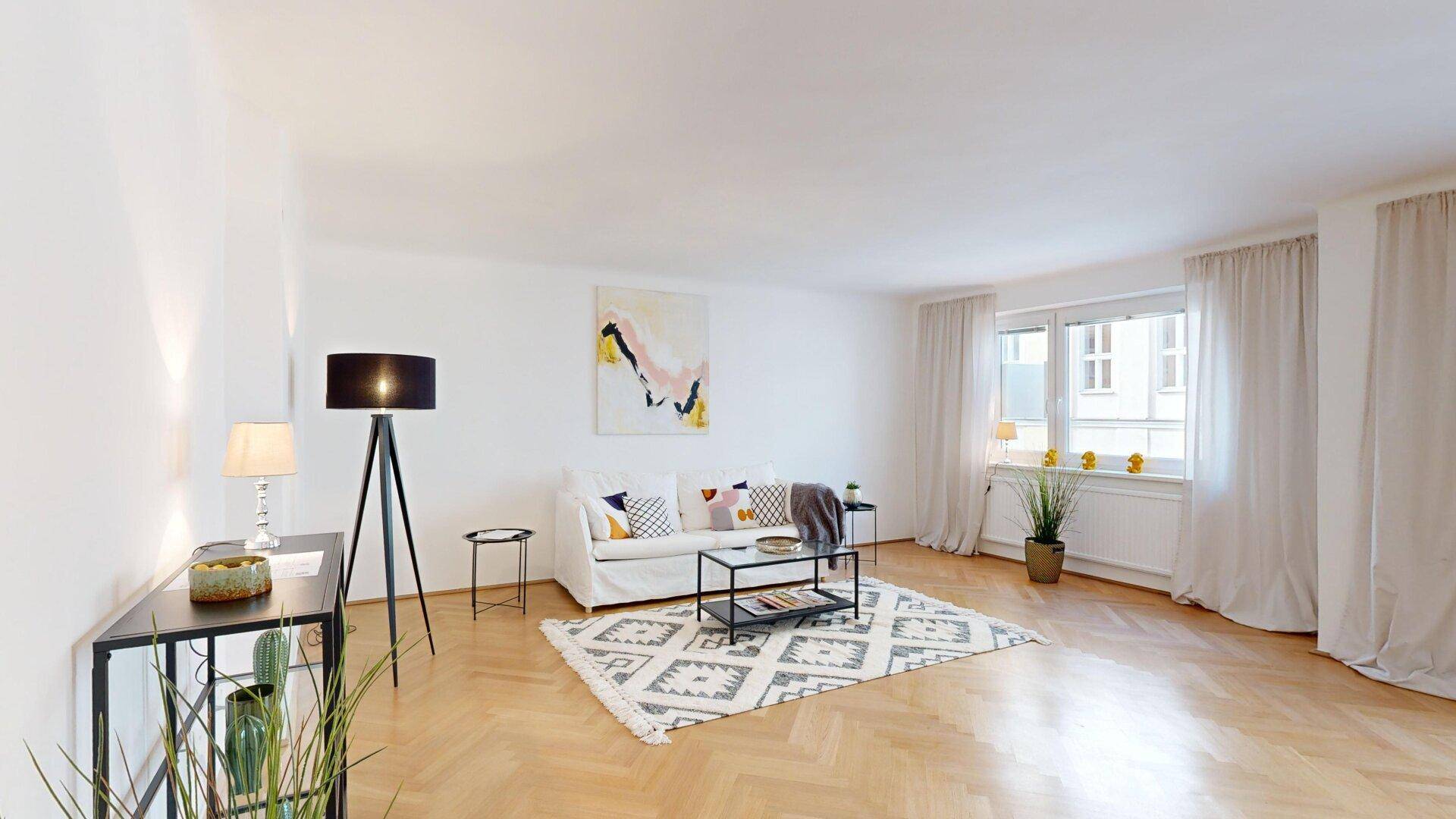 Gemütliches Wohnzimmer mit hellem Fischgrätparkett, modernem Sofa und stilvoller Stehlampe.