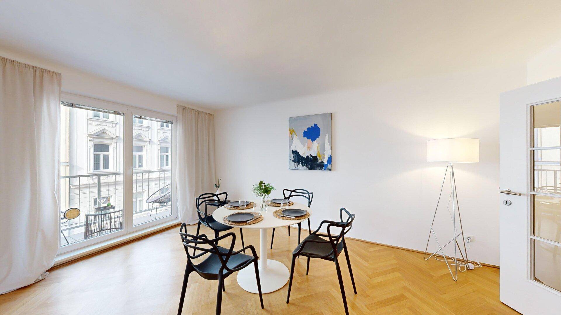 Heller Essbereich mit modernem Esstisch, schwarzen Stühlen und direktem Zugang zum Balkon.