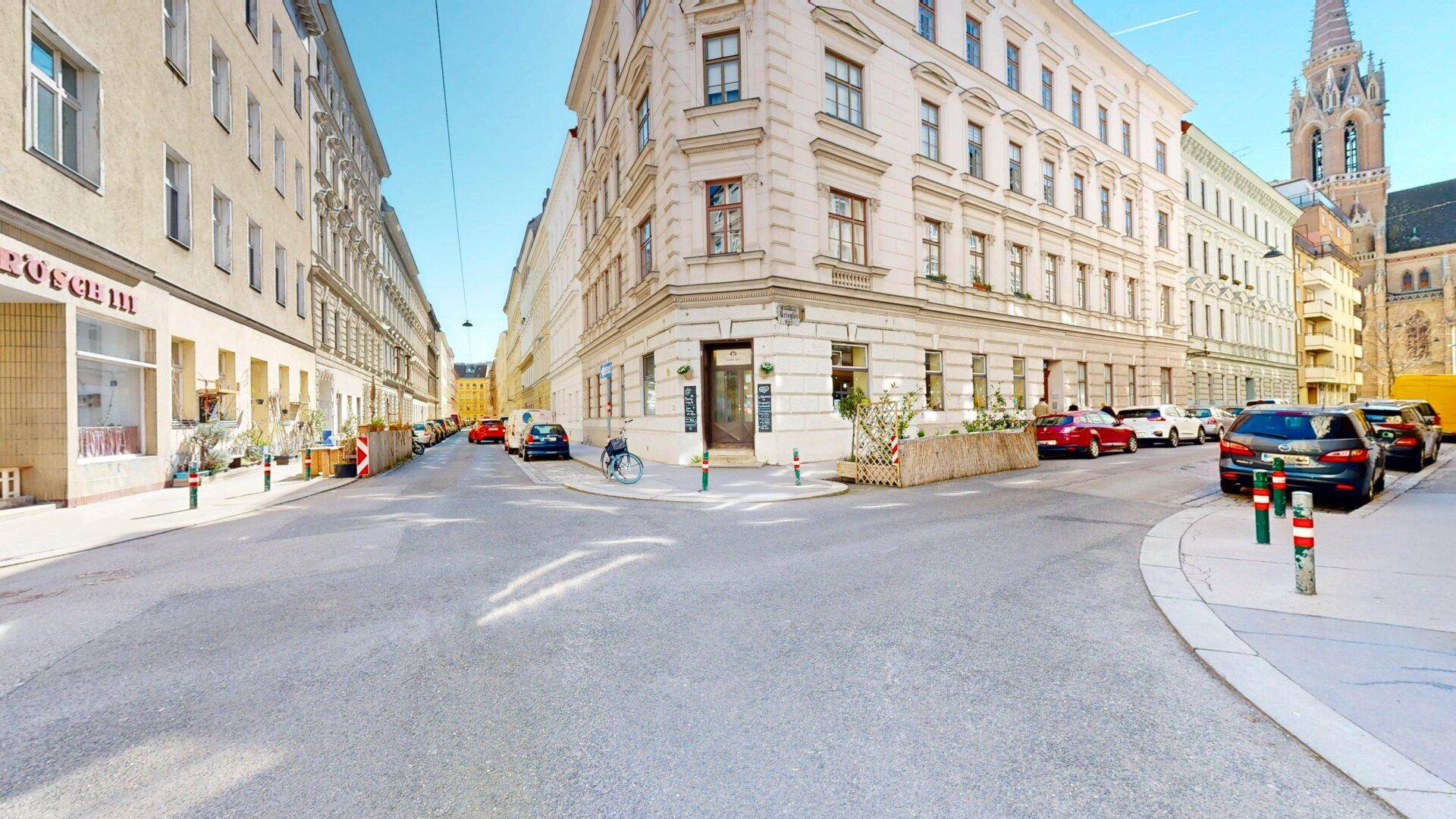 Historisches Eckgebäude in einer belebten Stadtstraße mit Geschäften und urbanem Flair.