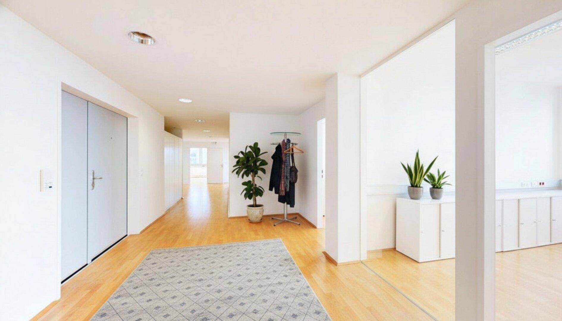 Heller Flur mit Holzfußboden, Garderobe und weißen Schränken, der zu weiteren Räumen führt.