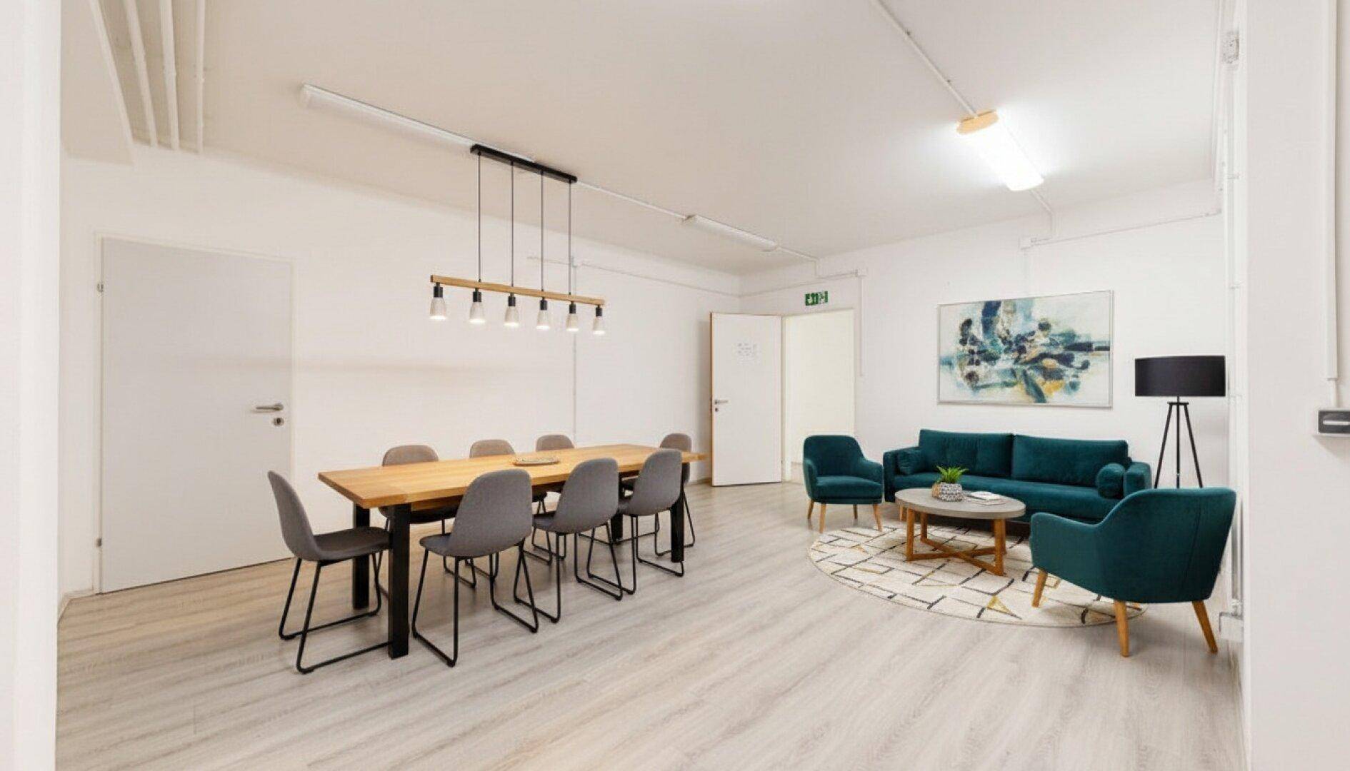 Vielseitiger Raum mit Konferenztisch und gemütlicher Lounge-Ecke, ideal für Besprechungen und Entspannung.