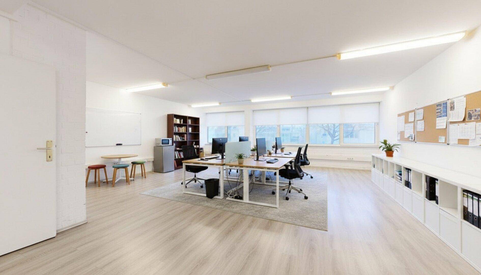 Flexibles Büro mit mehreren Arbeitsplätzen, Stauraum und einer Pinnwand für kreative Arbeit.