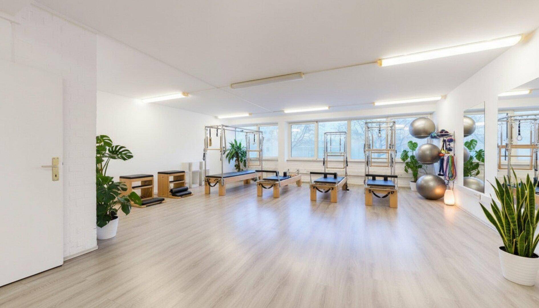 Helles Pilates-Studio mit Reformern, Gymnastikbällen und Spiegeln, bereit für Trainingseinheiten.