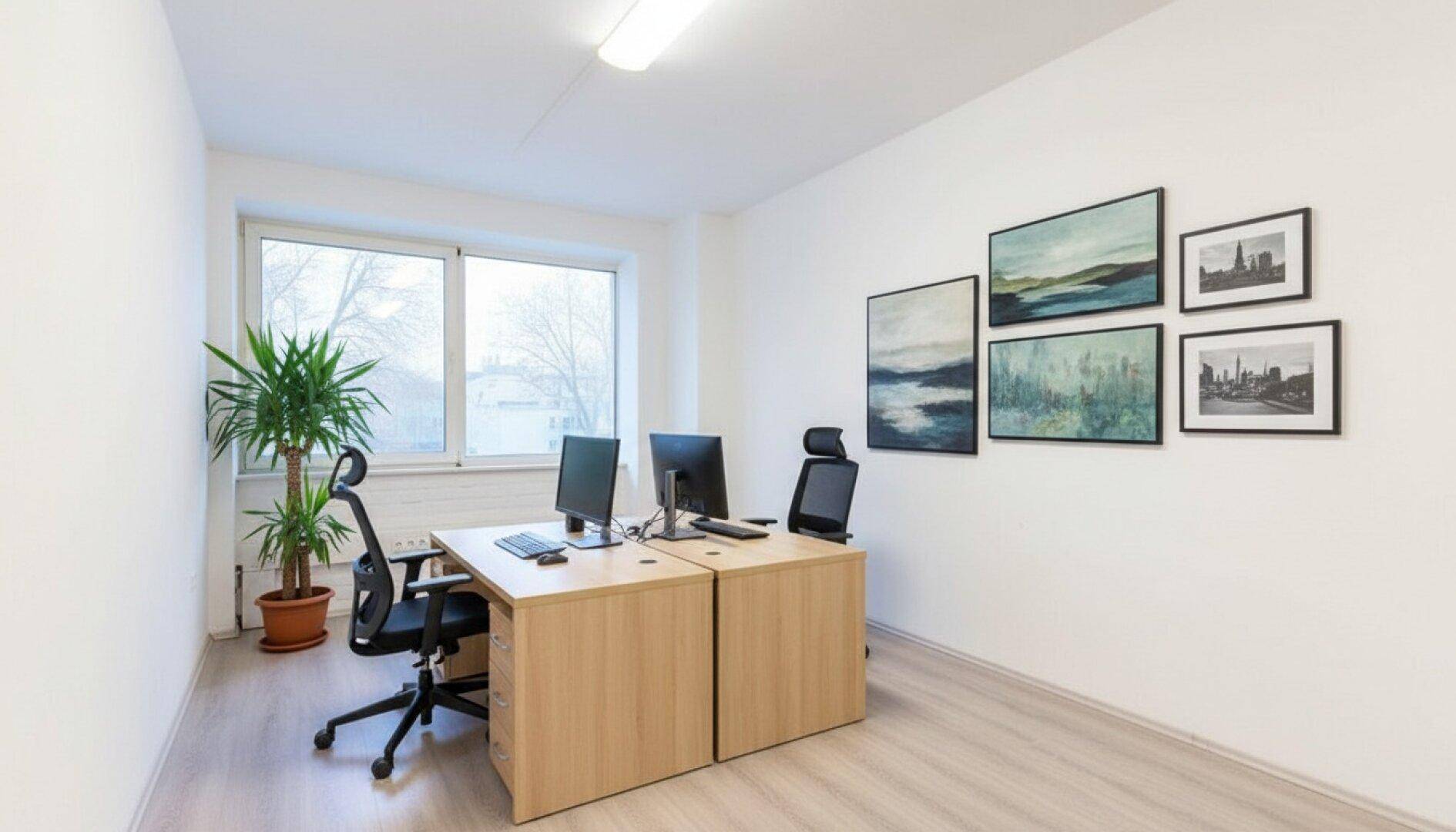Kompaktes Büro mit zwei Arbeitsplätzen, viel Tageslicht und dekorativen Wandbildern.