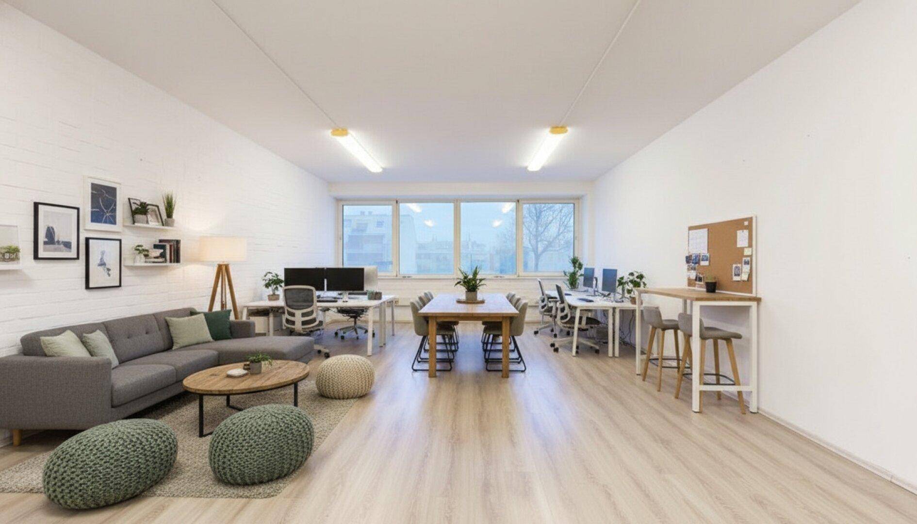 Großzügiges Open-Space-Büro mit Lounge-Bereich, Esstisch und mehreren Arbeitsplätzen, fördert Zusammenarbeit.