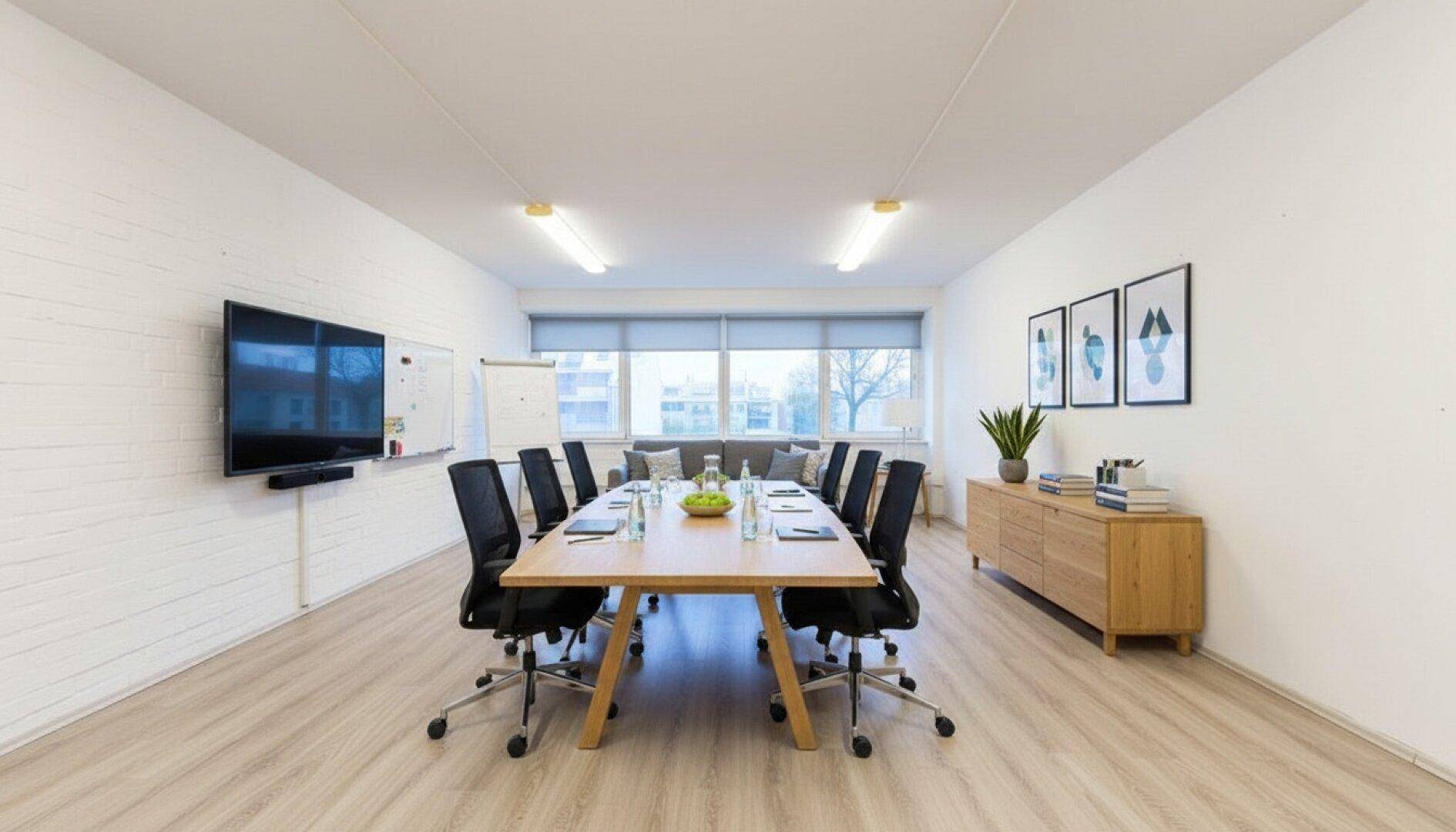 Heller Konferenzraum mit großem Holztisch, bequemen Stühlen und Whiteboard für produktive Meetings.