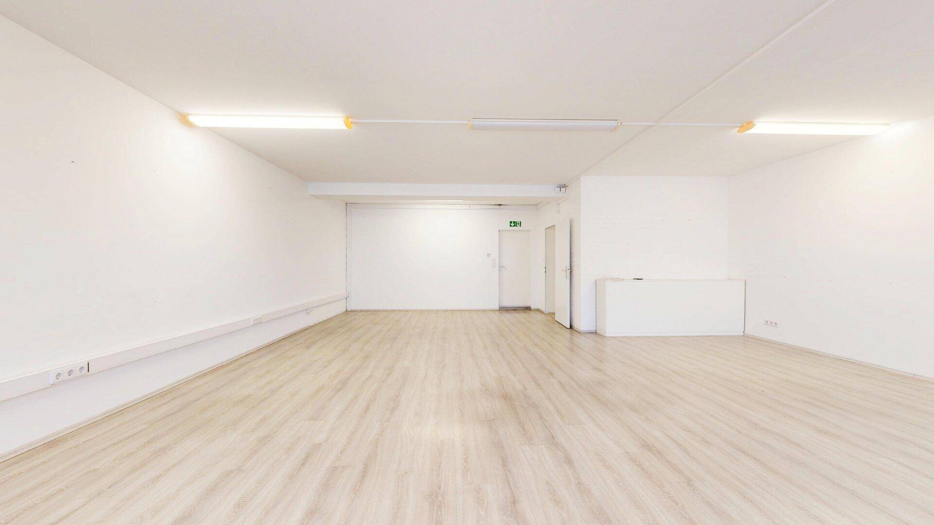 Heller, leerer Büroraum mit Laminatboden und einer großen Türöffnung, die vielseitige Nutzungsmöglichkeiten bietet.