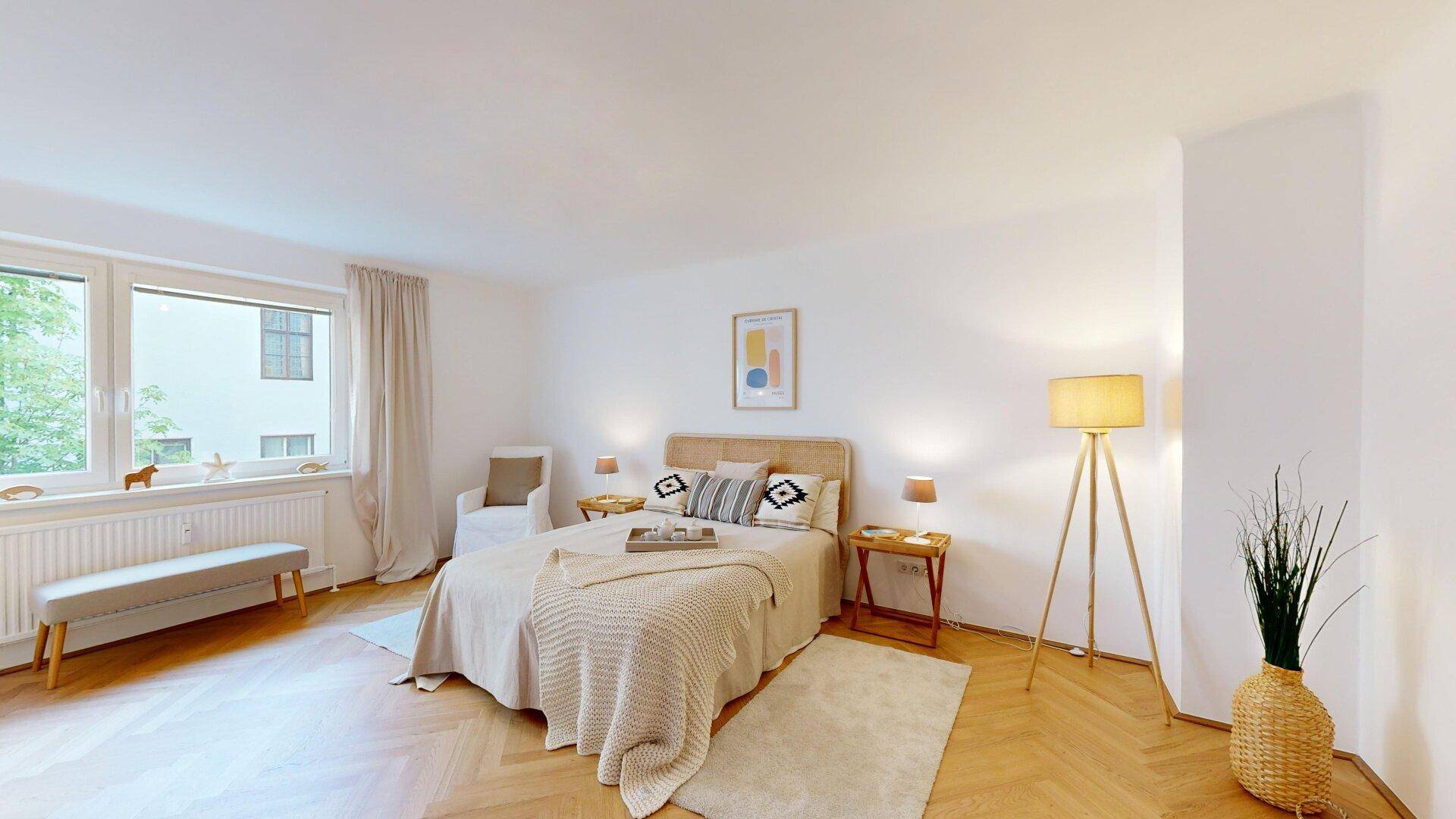 Gemütliches Schlafzimmer mit Fischgrätparkett, großem Fenster und heller, einladender Einrichtung.