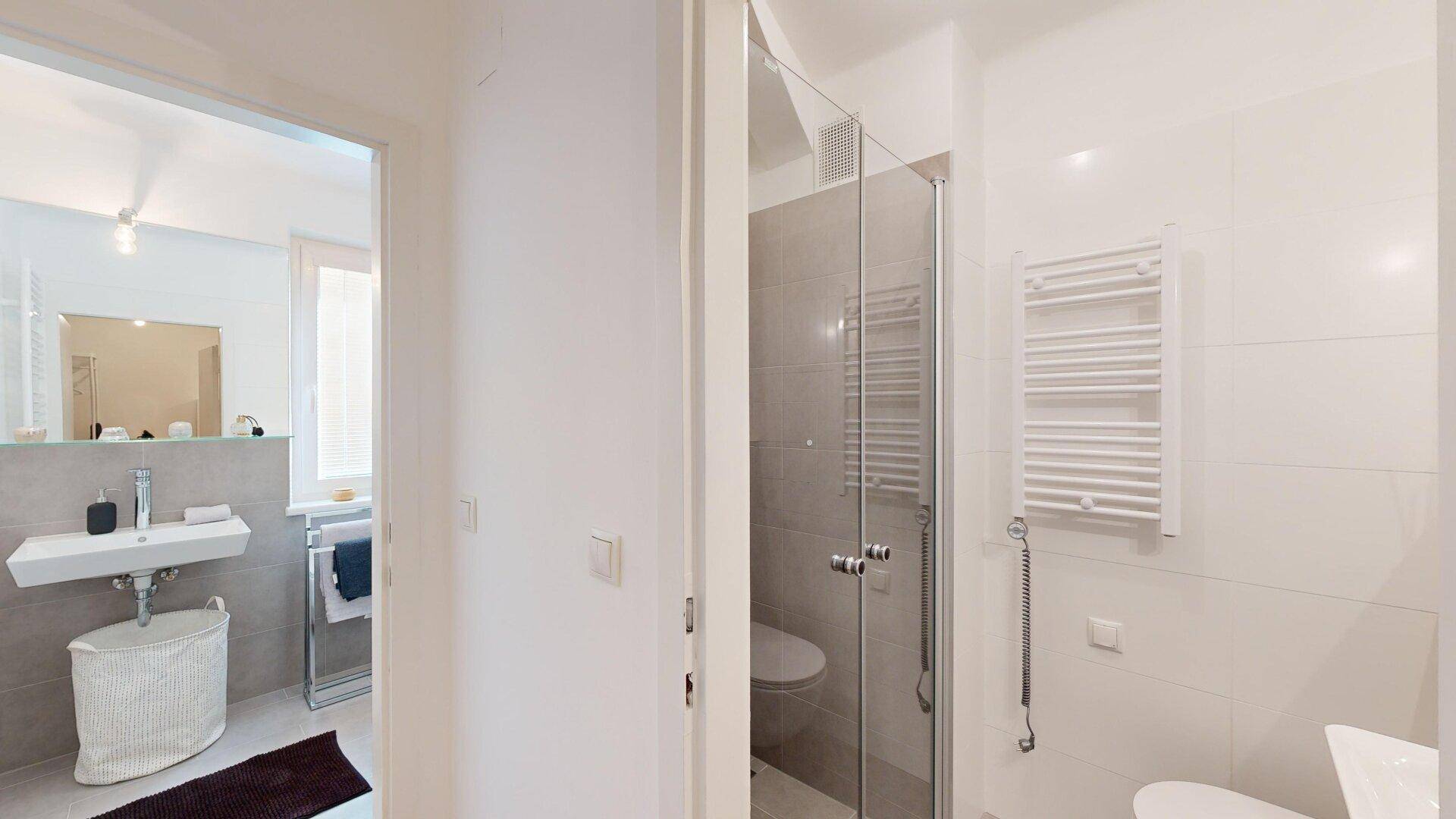 Modernes Badezimmer mit Duschkabine, Wand-WC und beheiztem Handtuchhalter.