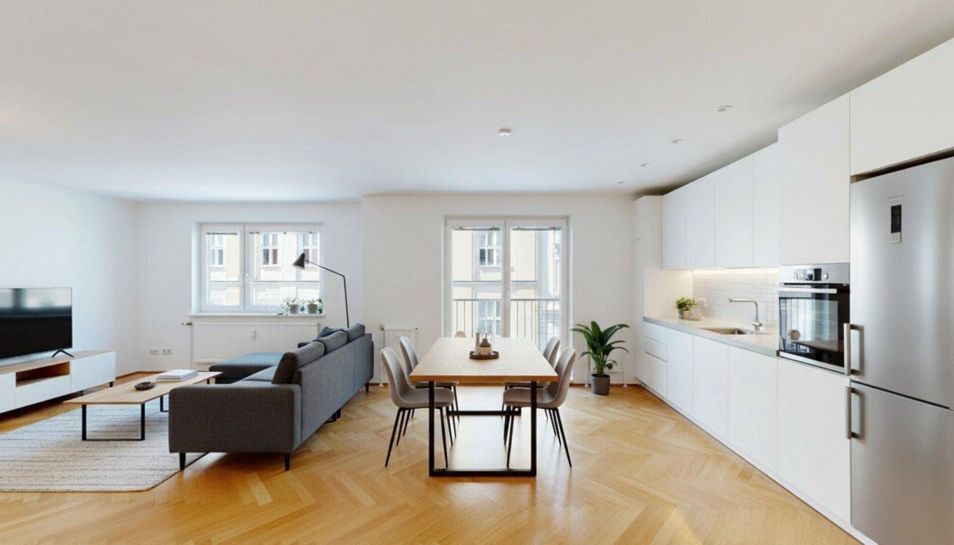 Moderner offener Wohn-Essbereich mit integrierter Küche, Parkettboden und Zugang zum Balkon.