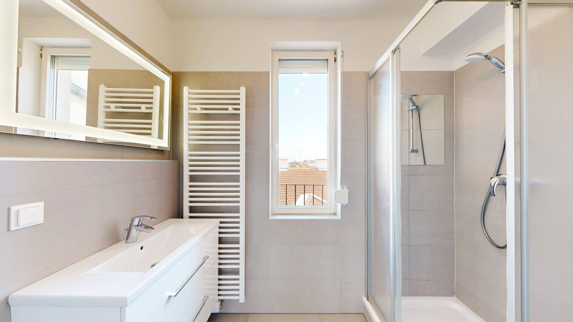 Helles Badezimmer mit moderner Dusche, Waschtisch und beheiztem Handtuchhalter.