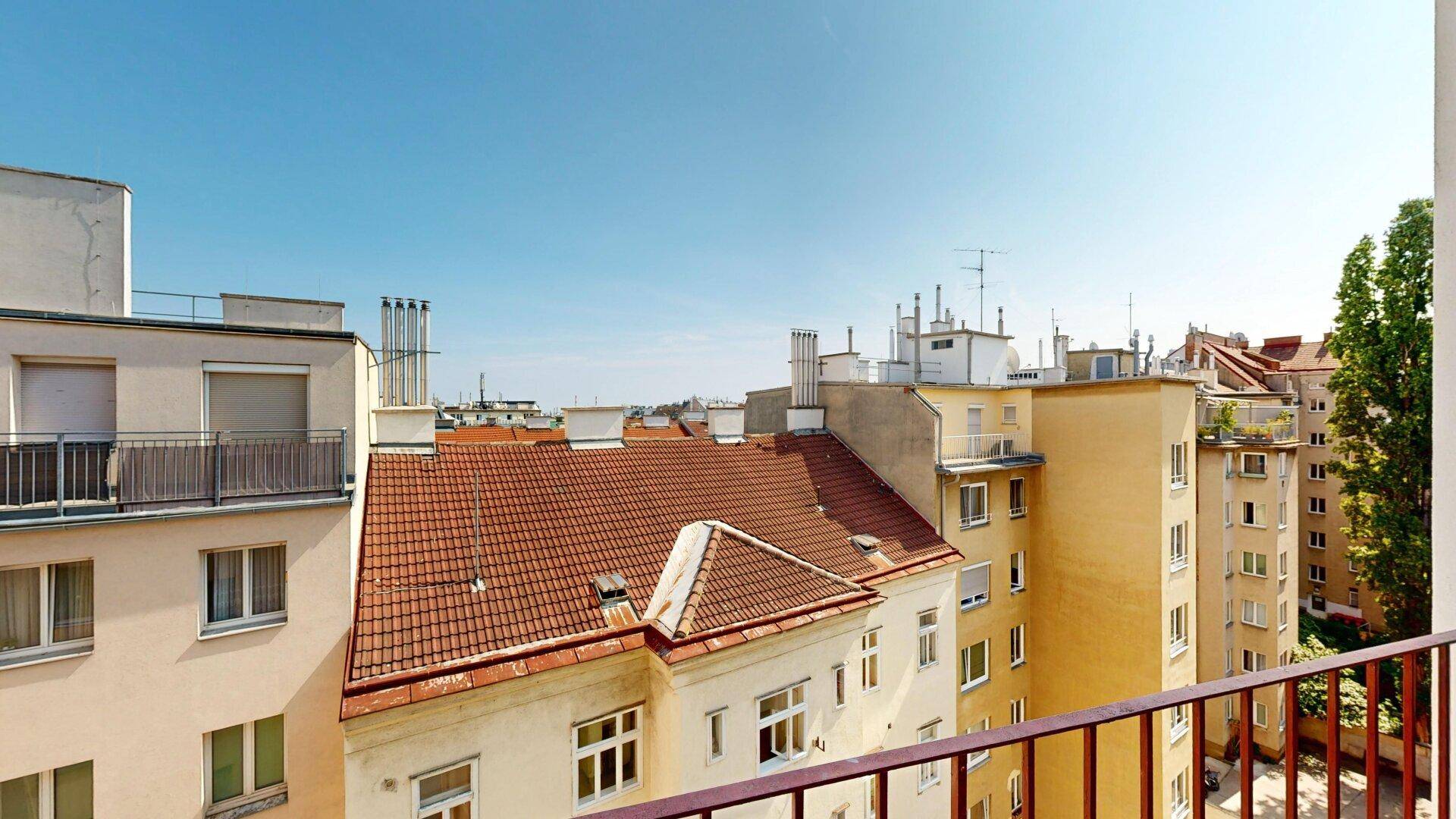 Blick von einem Balkon über die Dächer der Stadt mit traditionellen Ziegeldächern.