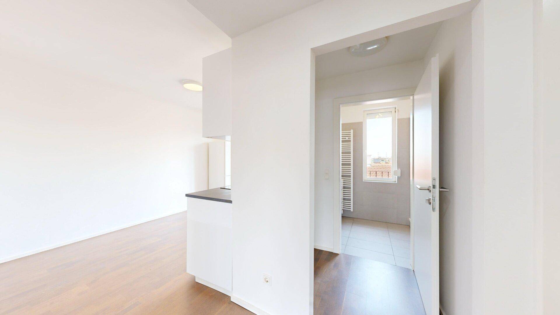 Heller Flur mit Holzboden, der zu einem Badezimmer und weiteren Räumen führt.