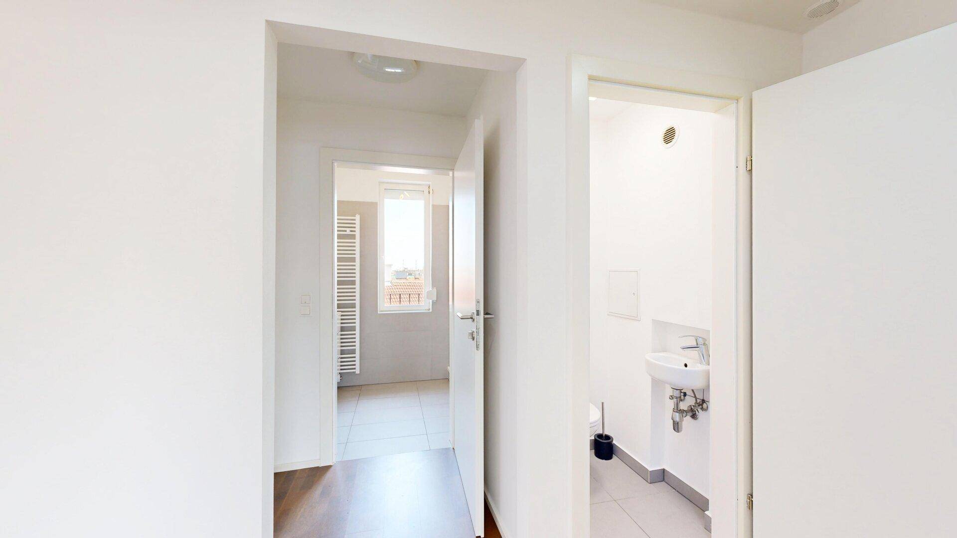 Eingangsbereich mit Zugang zu einem Badezimmer und einer separaten Gästetoilette.