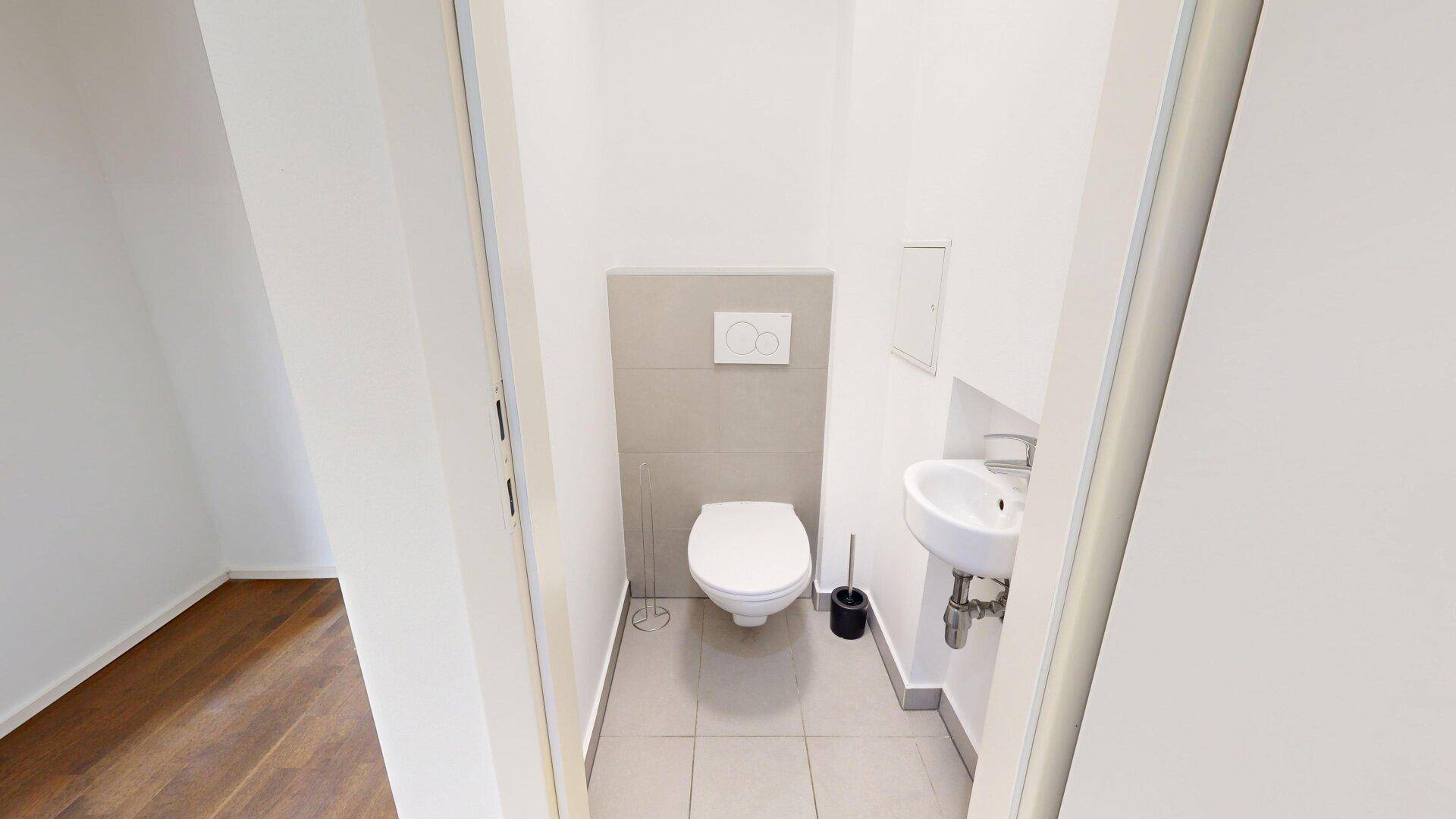 Kleine, separate Gästetoilette mit modernem Wand-WC und Waschbecken.